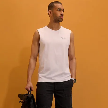 Hvit singlett, mørke shorts, hvite sneakers og sort ryggsekk.