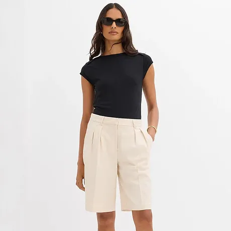Elegant kombinasjon av sort t-skjorte og kremfargede bermudashorts.