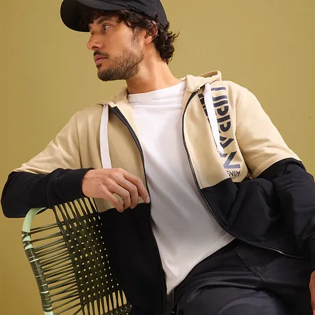 Urban stil: Beige jakke, hvit T-skjorte, mørk bukse og caps.