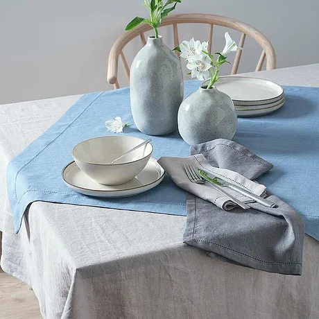Blå og grå duker pynter bordet, komplettert med enkle, hvite blomster­vaser.