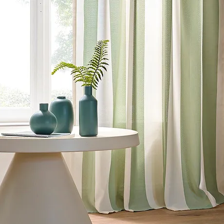 Lys, pastellgrønn og hvit gardin pynter vinduet og skaper en elegant atmosfære.