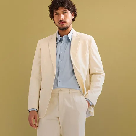 Elegant kremfarget dress med lyseblå skjorte og hvite sneakers.