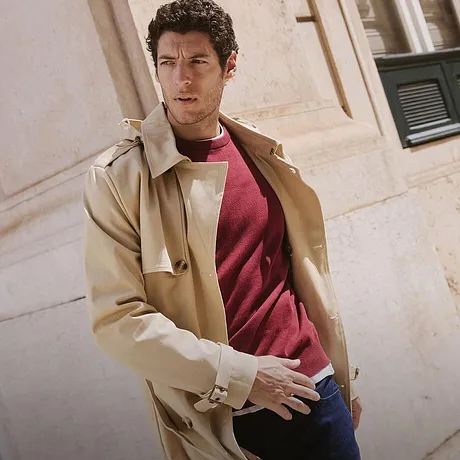 Elegant, beige frakk over rød genser og jeans. Ledig, urban høstlook.