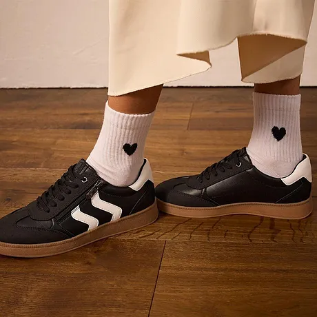 Hvite sokker med hjerter, sorte sneakers med hvite striper.