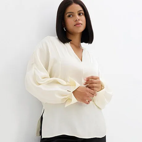 Elegant, hvit bluse med V-hals og vide ermer.