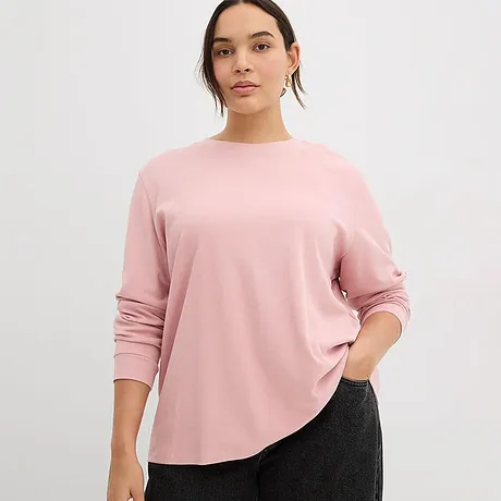En blek rosa, langermet topp med rund hals passer perfekt til den mørke buksen.