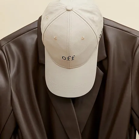 Beige caps og brun skinnjakke hengende på en kleshenger.