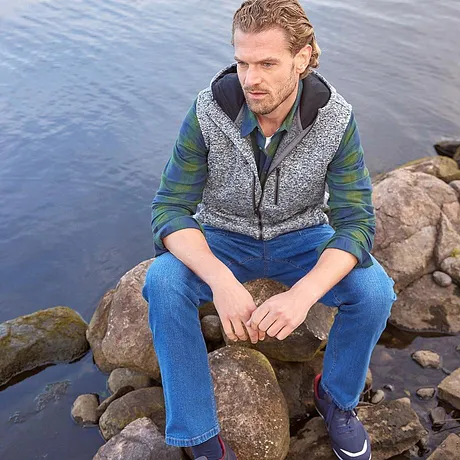 En mønstret vest over en grønn skjorte kombinert med bluejeans.