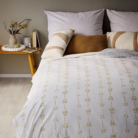 Hvitt sengesett, gyllent mønster og mange, dekorative puter.