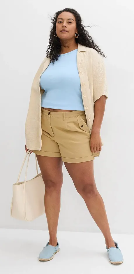 Sommerlig outfit med lyseblå topp, beige cardigan, khakifarget shorts og passende sko.
