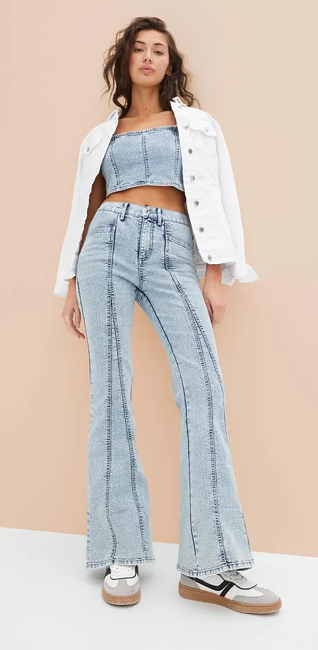 Trendy outfit i retrolook med hvit jeansjakke, tubetopp og jeans med utsvingte ben.