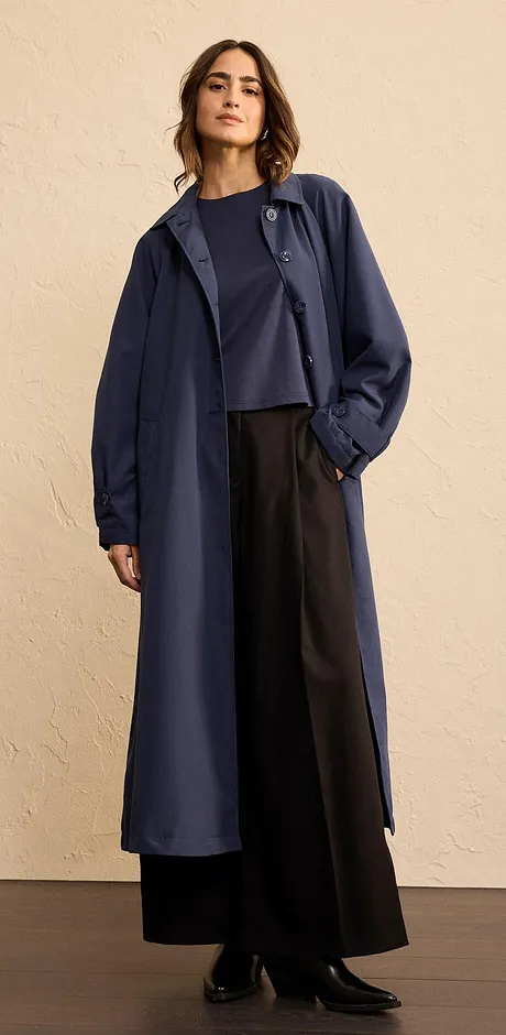 Elegant, lang og mørkeblå kåpe kombinert med vid bukse og stilren topp.