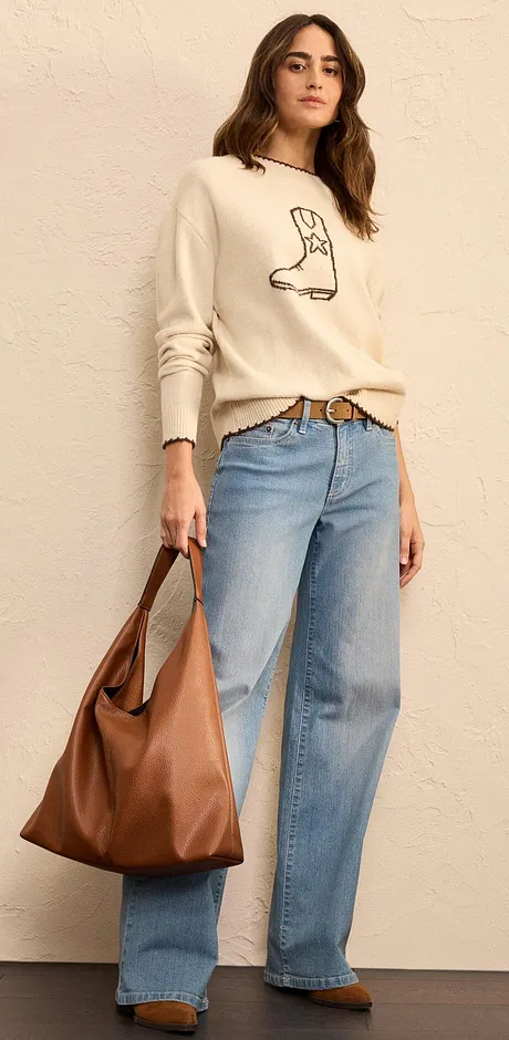 Kremfarget genser med støvel-trykk, vide jeans og brun, stor skinnveske.