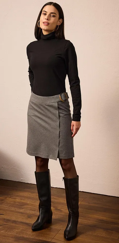 Elegant look med sort pologenser, grått skjørt og høye, sorte støvletter.