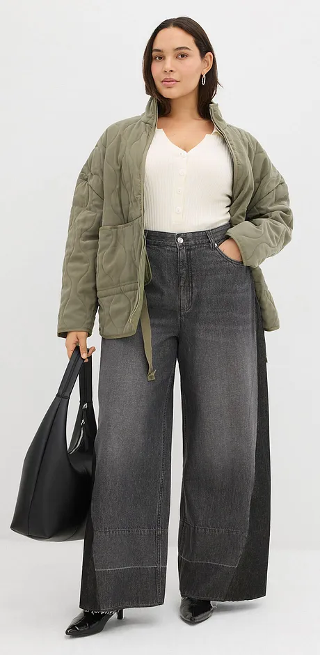 Olivengrønn, quiltet jakke, hvit topp og vide, grå jeans.