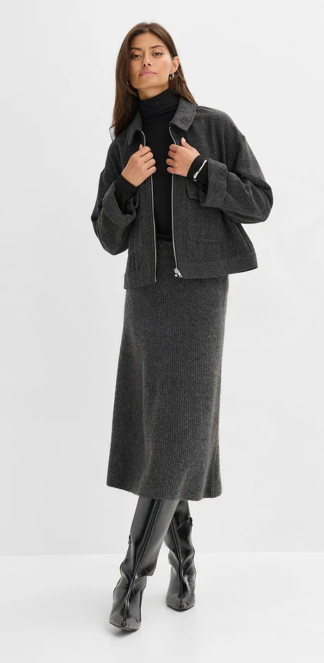 Grått ullskjørt, sort, høyhalset genser, kort jakke og knehøye skinnstøvletter.