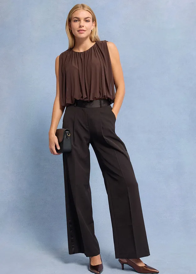 Brun, ermel&oslash;s topp og vid, m&oslash;rk bukse.