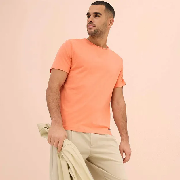 Ferskenfarget T-skjorte kombinert med lys bukse og matchende genser.