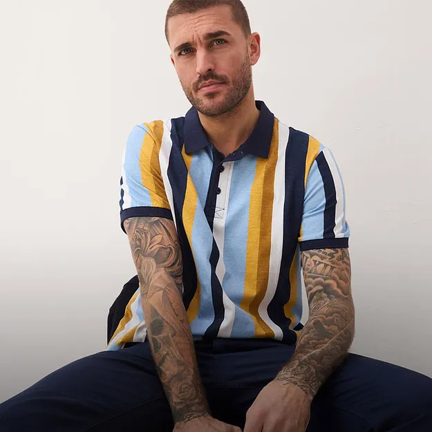 Bl&aring;, gul og hvit stripete poloskjorte. M&oslash;rk bukse.