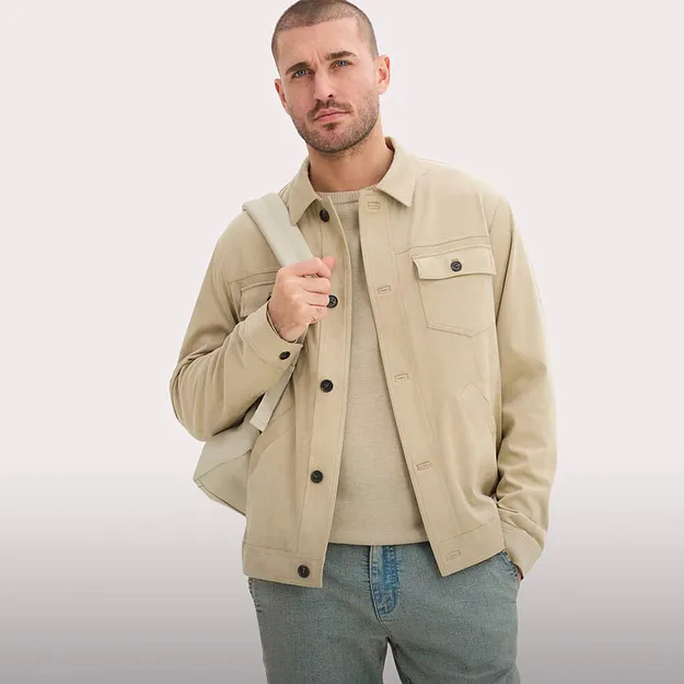 Beige jakke med knapper og brystlomme over lys genser. Kombinert med bluejeans.