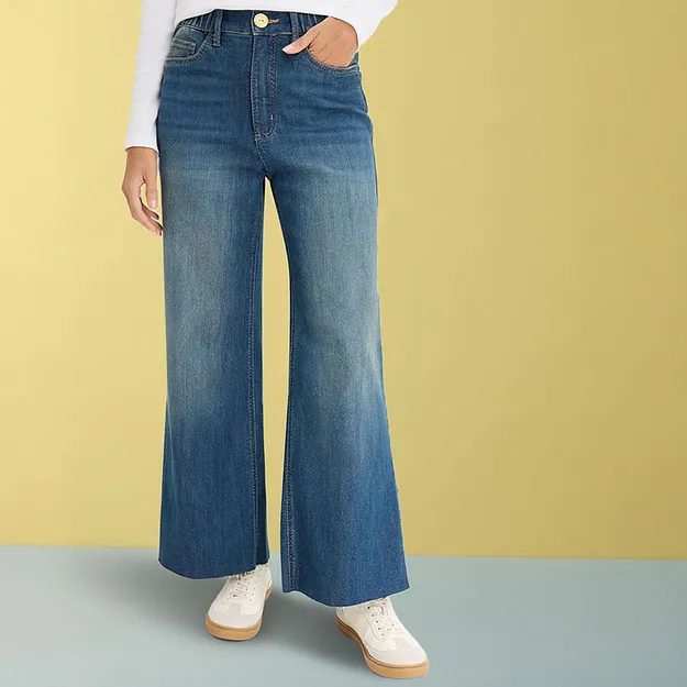 Vide jeans med hvit topp og lyse sneakers.