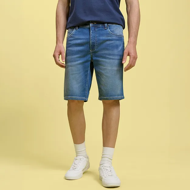 Avslappet denimshorts og bl&aring; T-skjorte kombinert med hvite sneakers og sokker.