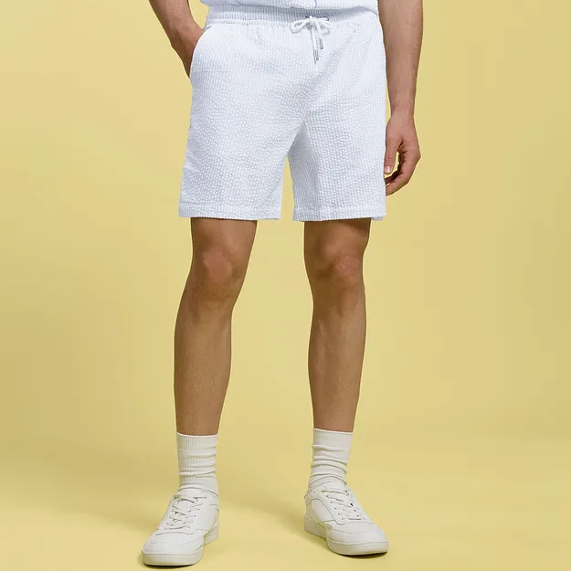 Hvit shorts med knyting, hvite sokker og sneakers.