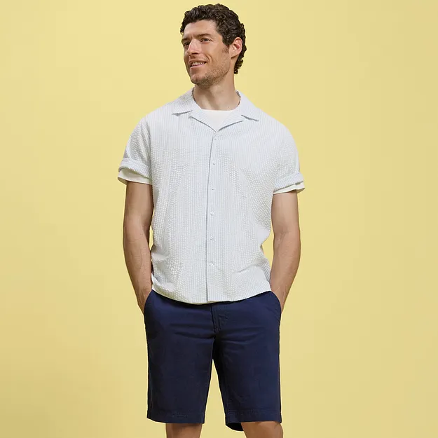 En person i hvit, kortermet skjorte og m&oslash;rkebl&aring; shorts.