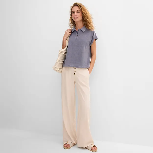 Elegant person i bl&aring;, avslappet T-skjorte og vid, beige bukse i avslappet stil.