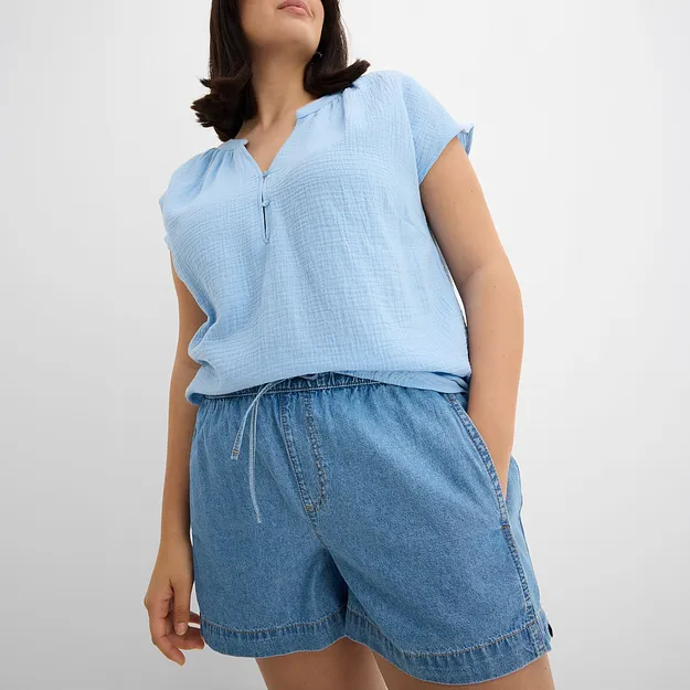 Flott sommerlook med lysebl&aring;, ermel&oslash;s topp med glidel&aring;s og avslappet denimshorts.