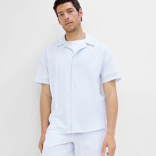Person i lysebl&aring; og hvit, kortermet skjorte med matchende shorts.