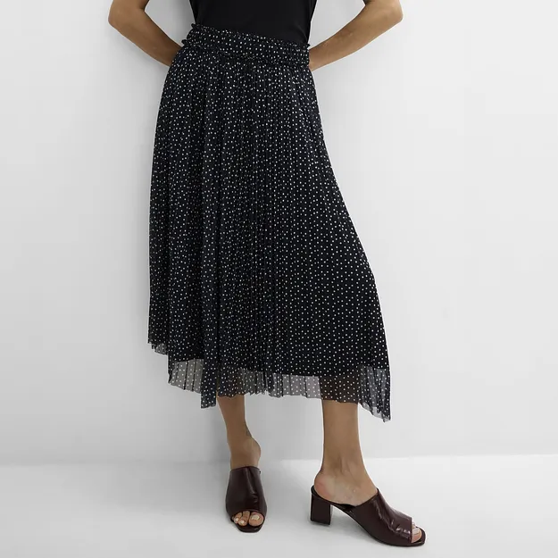 Stilren, sort topp, prikkete pliss&eacute;skj&oslash;rt og elegante, m&oslash;rkebrune slip-in sandaler.