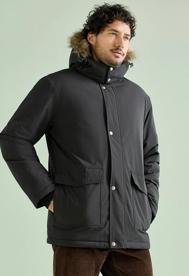 Hen in sort parkas med hette med fuskepels