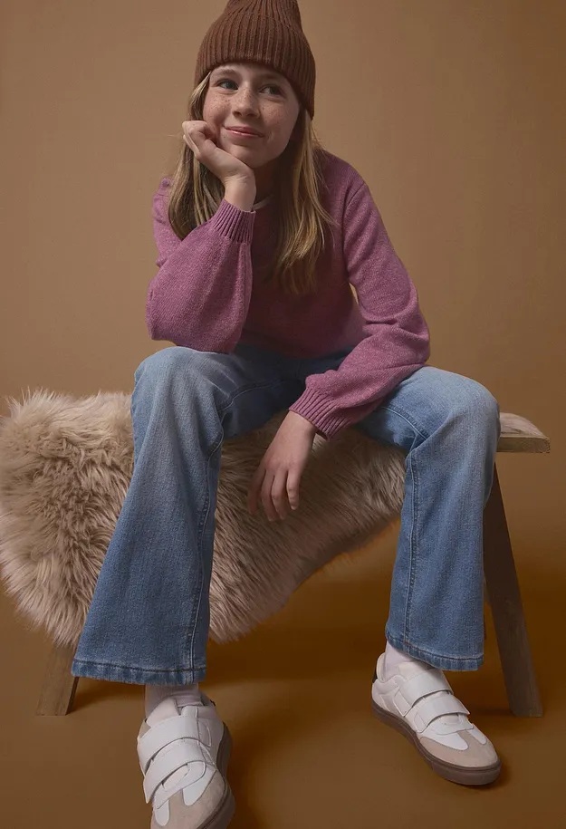 Brun lue, rosa genser, bl&aring; jeans og hvite sneakers med borrel&aring;s.