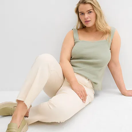Grønn topp med brede stropper, lyse jeans med frynset kant og sko i pastellfarger.