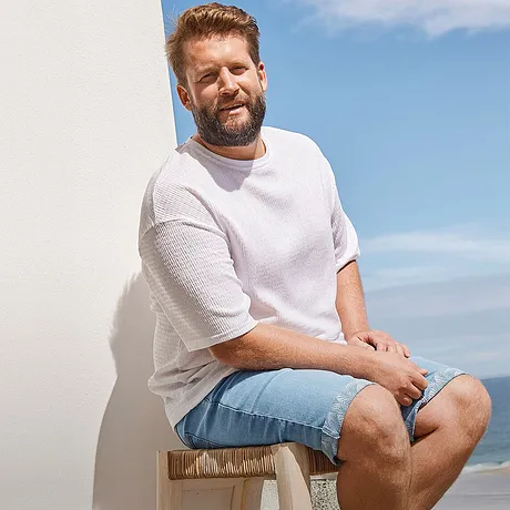 Avslappet sommerstil: Hvit T-skjorte og lyseblå jeansshorts, perfekt for stranddager.