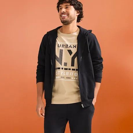 Avslappet look med beige T-skjorte, sort hettejakke & mørk sweatshorts.