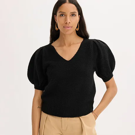 Sort genser med puffermer og V-hals kombinert med beige bukse.