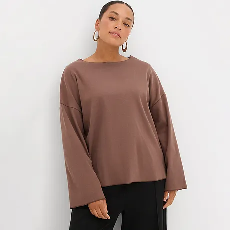 Brun, langermet topp med vide ermer kombinert med sort bukse.