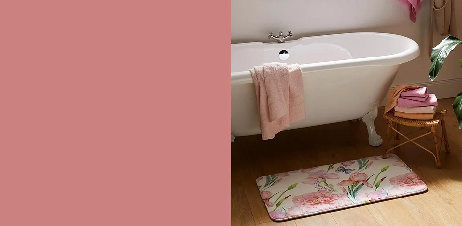 Håndklær i friske farger og blomstrete badematte gjør seg fint på badet med hvitt vintage badekar.