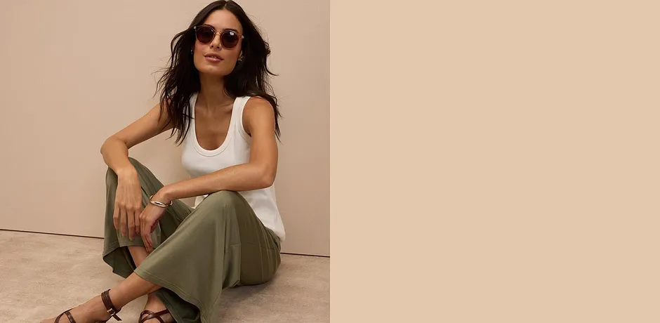 Hvit singlet, olivengrønne bukser og brune sandaler – en avslappet sommerlook med solbriller.
