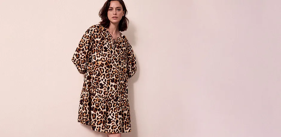 En luftig kjole med leopardmønster faller lett over skuldrene og ender like over kneet.