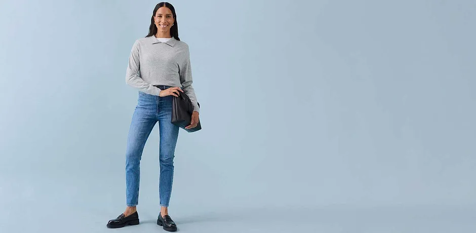 Lysegrå sweatshirt, blå skinny-jeans, mørke ballerinasko og brun skulderveske.