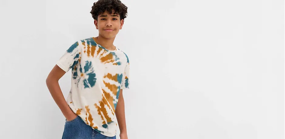 Moderne batikk-T-skjorte i blått og oransje, kombinert med klassiske jeans for en avslappet look.