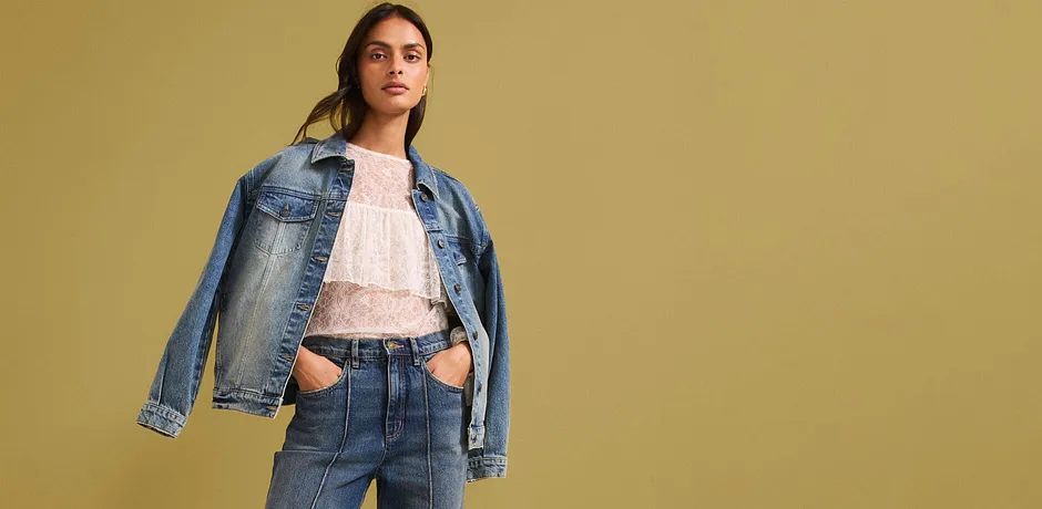 Casual denim-look med denimjakke, lys blondebluse og high-waist jeans for en moderne stil.