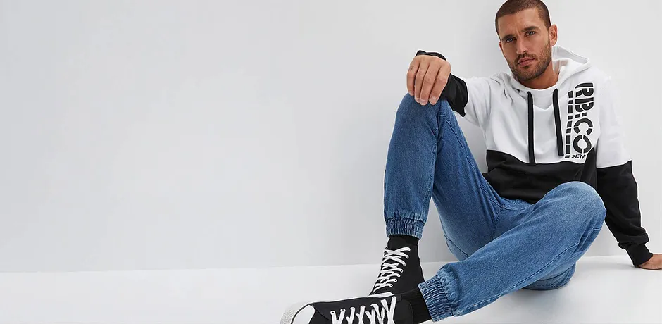 Ledig stil med jeans, tofarget hettegenser og ankelhøye sneakers.