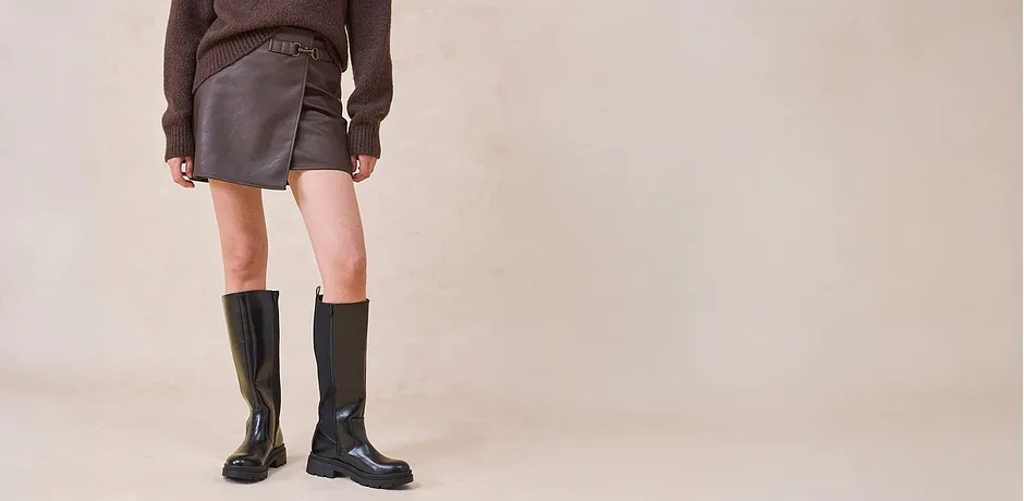 Skinnskjørt og knehøye støvletter kombinert med en brun genser.