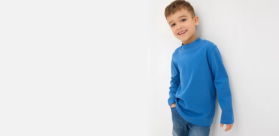 Blå genser med lange ermer og klassiske bluejeans.