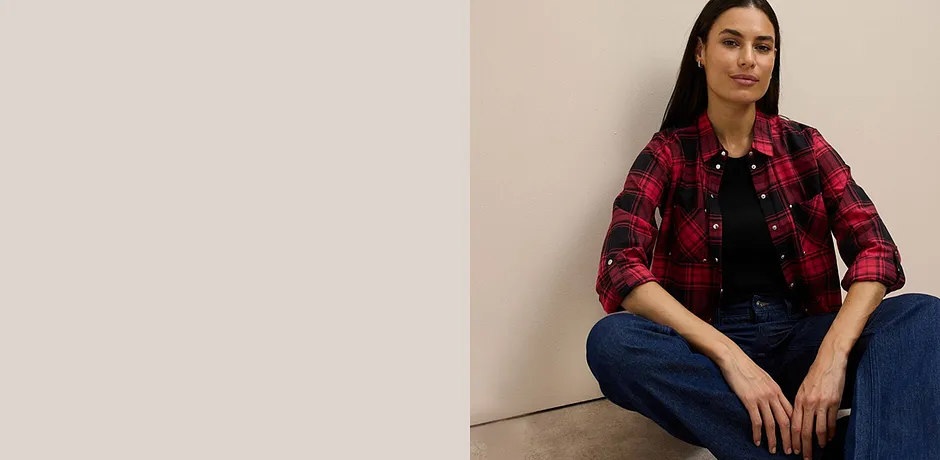 Rutete skjorte i rødt og sort over sort topp kombinert med klassiske jeans.