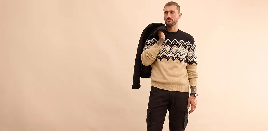 Stilfull look med sort vinterjakke, mønstret genser og jeans for kalde dager.